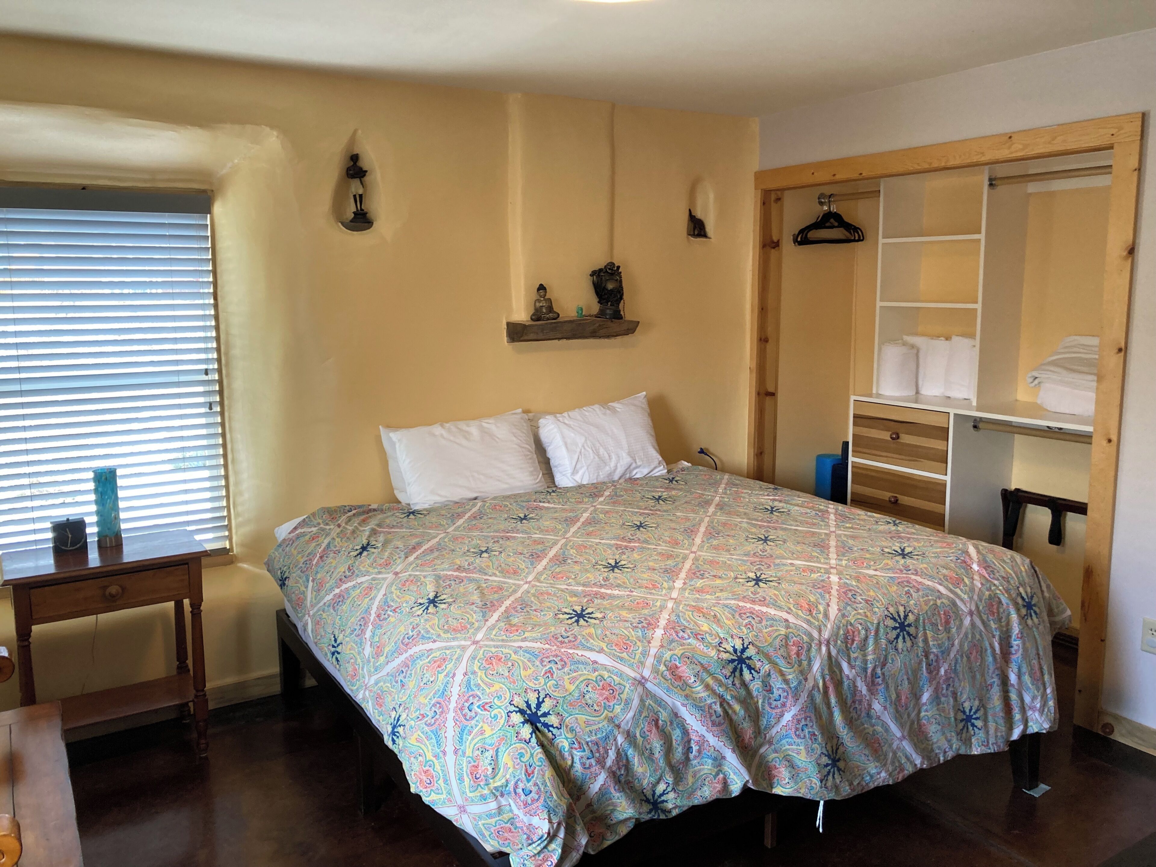 A bedroom with a bed, bedside table, and a wardrobe with hanging space.