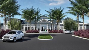 A modern building with a symmetrical facade, palm trees, and a central circular driveway. - Brand New 10BR 8BA/Themed BR/PrivatePool/SPA 16276 (Clermont)