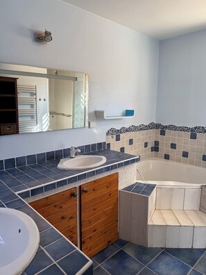 A bathroom with a bathtub, a sink, and a mirror.