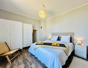A bedroom with a bed, bedside tables, a wardrobe, a chair, and a hanging light fixture. - - Casa Vista - Panoramic sea view - 50 meters from the beach - (Borgo)