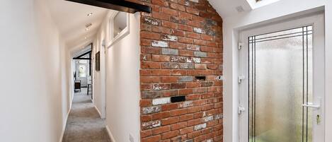 A hallway with a brick wall, a door with frosted glass, and a skylight.
