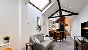 Un espacio habitable moderno con techo estilo loft, un sofá, una zona de comedor y un televisor.