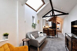 A modern living space with a loft-style ceiling, a sofa, a dining area, and a television. - Bright And Airy Cottage Close To Salisbury Centre (Salisbury)