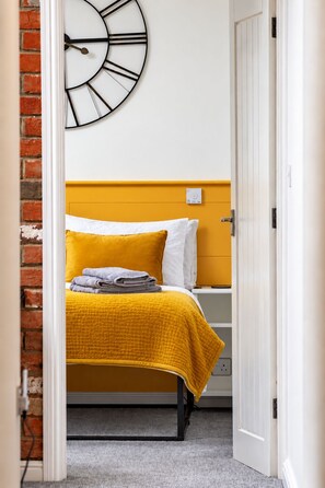 Een kamer met een bed, een klok en een deur.