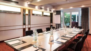 A conference room with a long table, chairs, a projector screen, and a view of greenery outside. - 1 Person Holiday Park Home in Offenburg (Offenburg)