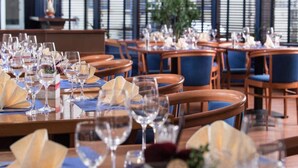 A restaurant with tables set for dining, featuring wooden chairs and a view through large windows. - 1 Person Holiday Park Home in Offenburg (Offenburg)