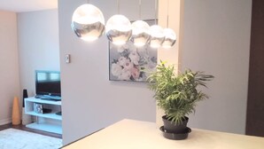 A modern living room with a flat-screen TV, a potted plant, and a floral painting on the wall. - Cozy Fully Furnished Apt w/ Parking (Toronto)