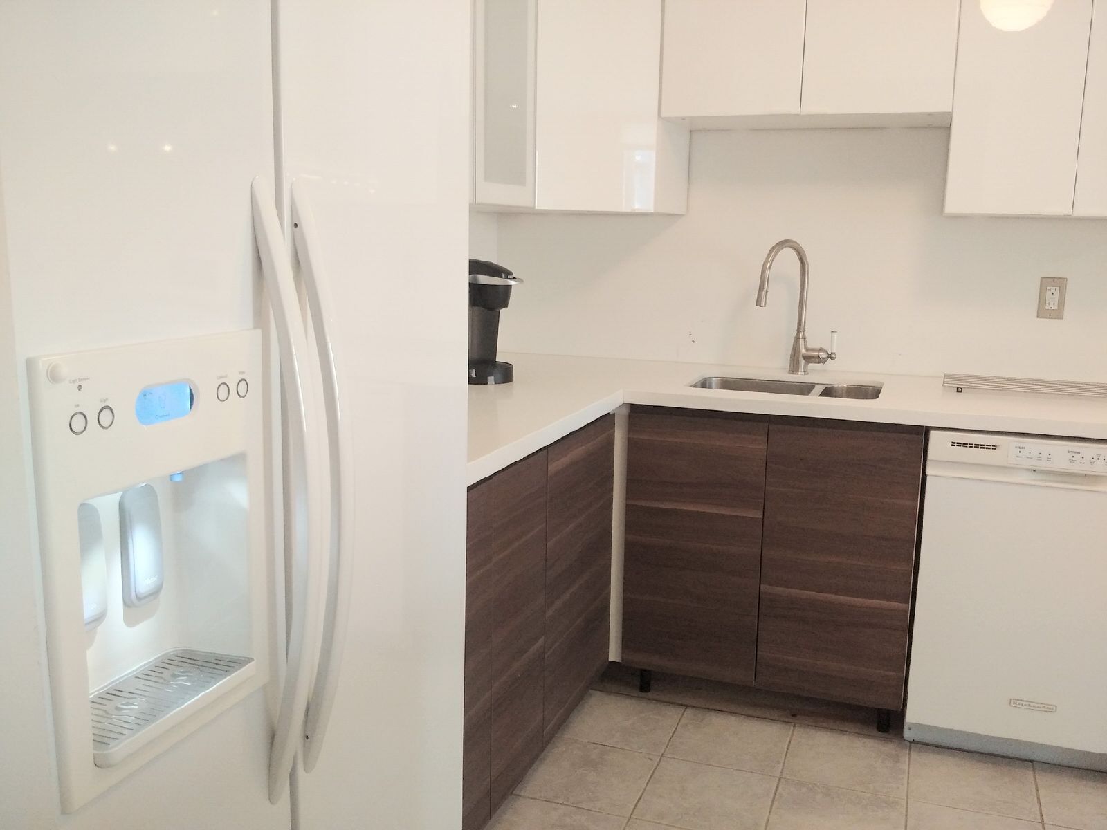 A modern kitchen with a built-in refrigerator, a coffee maker, a sink, and a dishwasher.