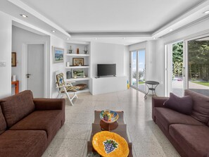Ein modernes Wohnzimmer mit zwei Sofas, einem Couchtisch, einem Fernseher und einem Bücherregal.