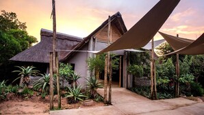 A house with a thatched roof, surrounded by plants and a clear sky. - Room-royal Thonga Safari Lodge - Private (uMhlabuyalingana)
