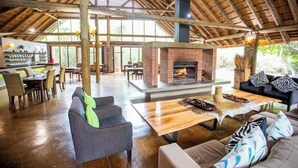 A spacious indoor area with a high ceiling, a brick fireplace, and a dining area with tables and chairs. - Room-royal Thonga Safari Lodge - Private (uMhlabuyalingana)