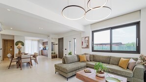 A spacious living area with a large sectional sofa, a wooden coffee table, and a dining table with chairs. - Verde De Luna Villa (Hersonissos)