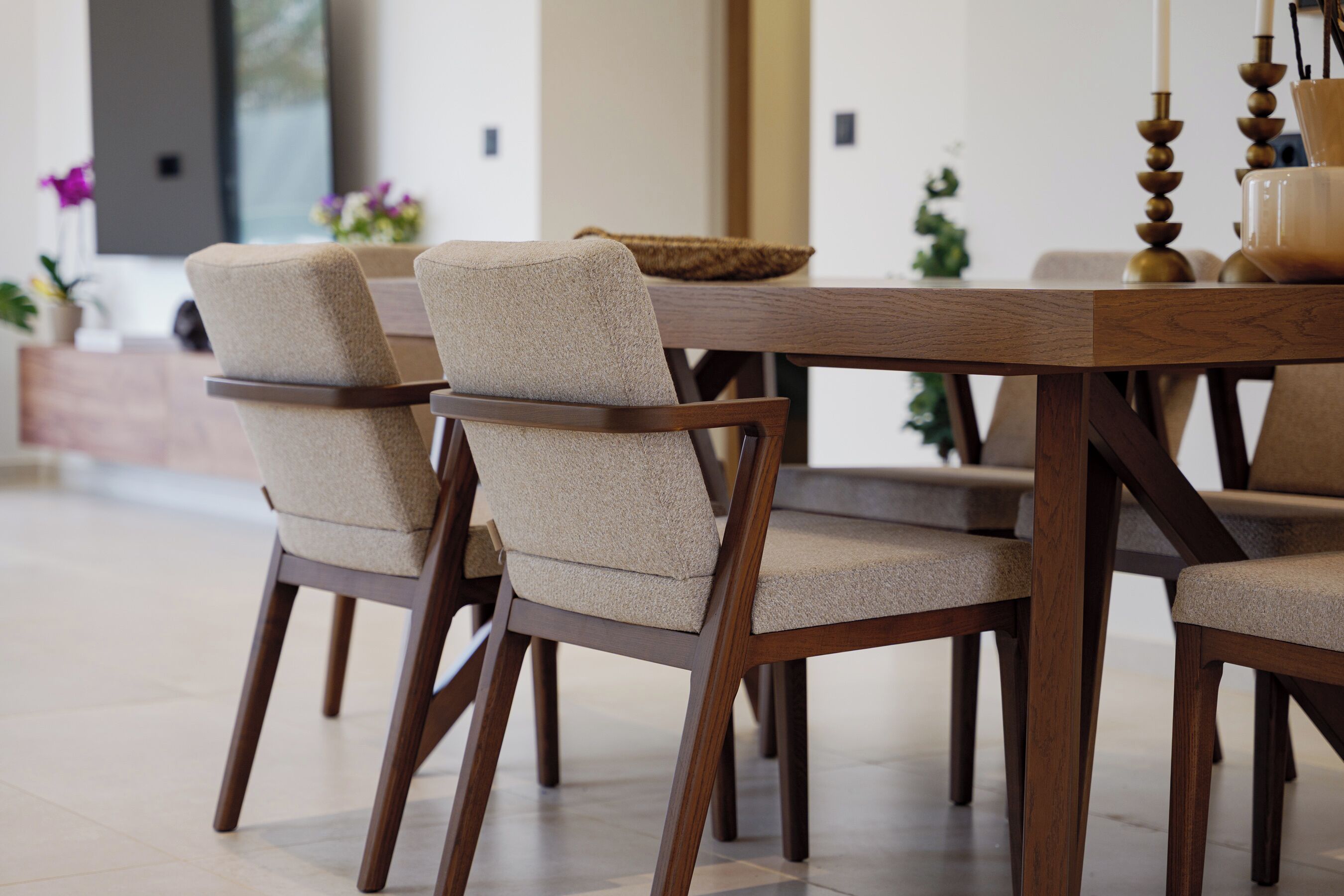 A dining area with a wooden table and chairs, a woven basket, and a candle holder.