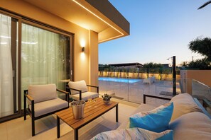 Ein moderner Außenbereich mit Pool, Holztisch und einer Couch.