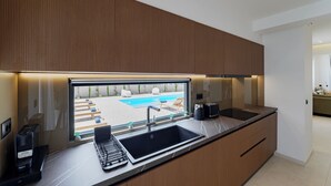 A modern kitchen with a built-in sink, a coffee machine, and a view of a pool. - Verde De Luna Villa (Hersonissos)