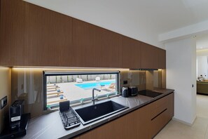 Eine moderne Küche mit integriertem Spülbecken, einer Kaffeemaschine und Blick auf einen Pool.