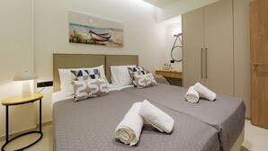 A hotel room with a bed, a nightstand, a lamp, a painting, and a wardrobe. - Verde De Luna Villa (Hersonissos)
