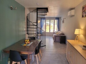 Ein Essbereich mit einer Wendeltreppe, einem Tisch mit Stühlen und einer Küchenzeile mit Arbeitsplatte und Schränken.