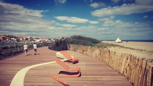 A wooden boardwalk with lounge chairs, a fence, and a beach in the background. - Gîte des Tamarins - Saint-Pierre la Mer - Aude (Fleury)