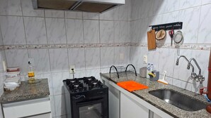 Una cocina con estufa a gas, lavamanos y armarios blancos.