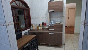 Una cocina compacta con una mesa de madera, una silla, un mueble empotrado y una ventana con marco de madera.