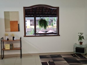 A room with a window, a bookshelf, a potted plant, and a patterned rug. - PUC Room. Eucharistic Heart. Garage subject to availability.  (Belo Horizonte)