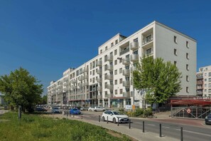 Ein mehrstöckiges Wohngebäude mit Balkonen, einem Fußweg und einer Straße mit Autos.
