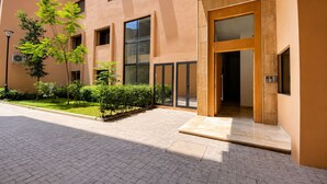 Un edificio moderno con entrada pavimentada, grandes ventanales y un jardín bien cuidado.