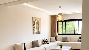 Una sala de estar moderna con sofá, mesa de comedor y un amplio ventanal.
