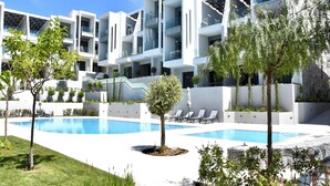 Un hotel moderno con piscina, diversi balconi e un giardino curato.