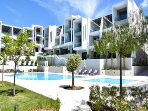 Ein modernes Hotel mit Pool, mehreren Balkonen und einem gepflegten Garten.