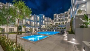 Un hotel moderno con area piscina, numerosi balconi e posti a sedere all'aperto.