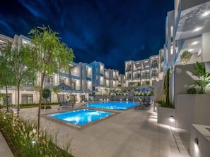 Ein modernes Hotel mit Poolbereich, mehreren Balkonen und Sitzgelegenheiten im Freien.
