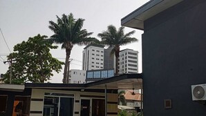 Ein Schwimmbecken mit einem modernen Gebäude im Hintergrund, Palmen und einem klaren Himmel.