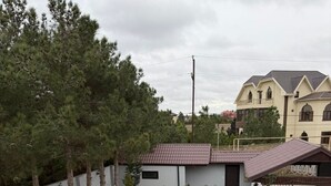 A residential area with a swimming pool, a covered patio, and a two-story house with a red-tiled roof. - Sea Walk Villa (Баку)