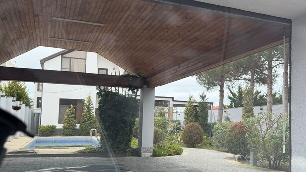 A car's interior with a view of a covered outdoor area, a swimming pool, and a building in the background. - Sea Walk Villa (Баку)