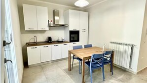 Eine moderne Küche mit weißen Schränken, einem Holztisch und blauen Stühlen.