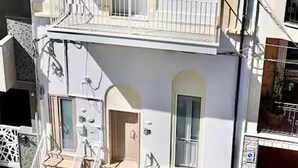 Ein mehrstöckiges Gebäude mit Balkon, Treppe und Tür.