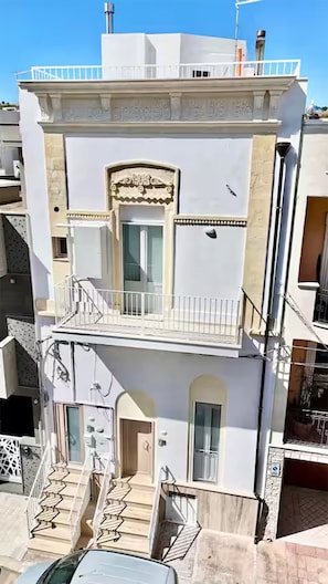 Ein mehrstöckiges Gebäude mit Balkon, Treppe und Tür.