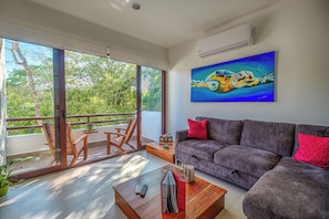 A modern living room with a balcony, a sofa, a coffee table, and a painting.