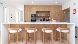 Eine moderne Küche mit Holzausstattung, einer zentralen Kochinsel mit Sitzgelegenheiten und eingebauten Geräten.