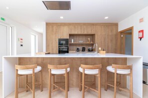 Eine moderne Küche mit Holzausstattung, einer zentralen Kochinsel mit Sitzgelegenheiten und eingebauten Geräten.