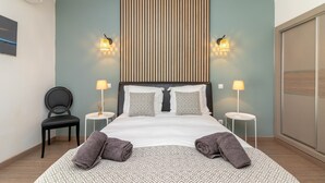 Ein Hotelzimmer mit einem großen Bett, zwei Nachttischen mit Lampen, einem Sessel und einer Wand-Klimaanlage.
