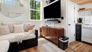 A modern interior with a sofa, TV, wooden cabinet, and kitchen area.