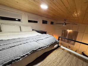 Ein Schlafzimmer mit Bett, Deckenventilator, Kamin und Fenster.