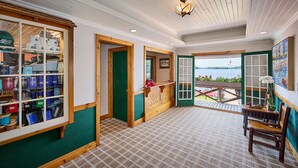 Habitación de hotel con vista al lago, un banco de madera y una mesa con un jarrón de flores.