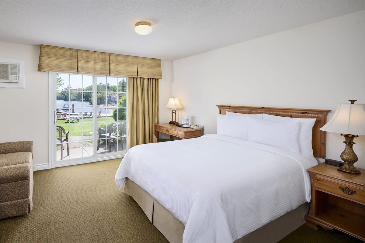 A hotel room with a large bed, a television, a desk, and a window with a view of the outdoors.