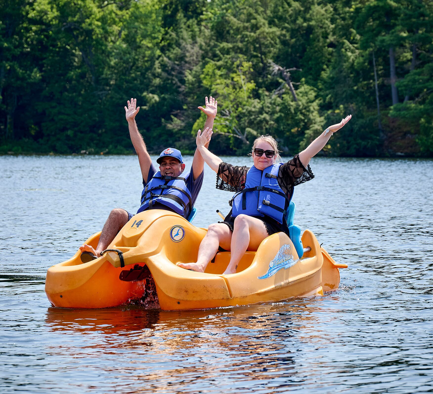 Two people on a yellow raft with water splashing around.