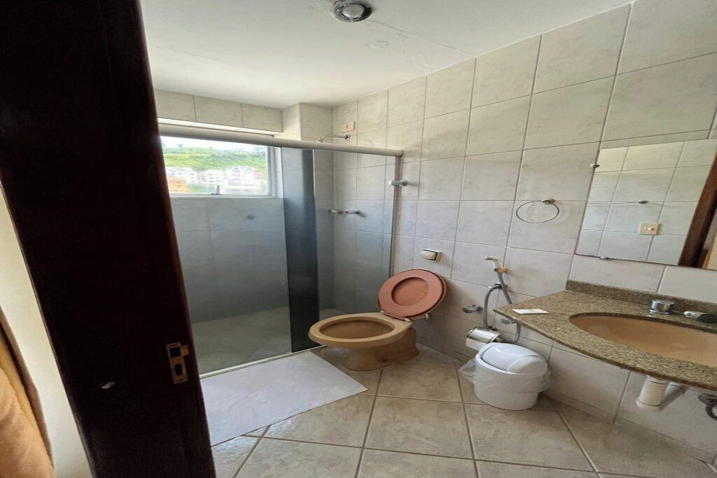 A bathroom with a shower, toilet, sink, and a glass door leading to a balcony.