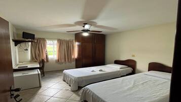 Een kamer met twee bedden, een bureau, een televisie en een plafondventilator.